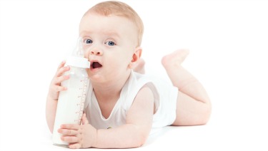 isolated on white, baby caucasian boy in white shirt lies with milk bottle Baby Formula